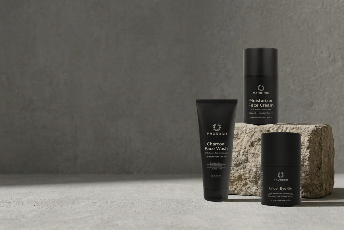 PAURUSH Charcoal Face Wash, Moisturizer Face Cream and Under Eye Gel for men on a stone block against grey concrete